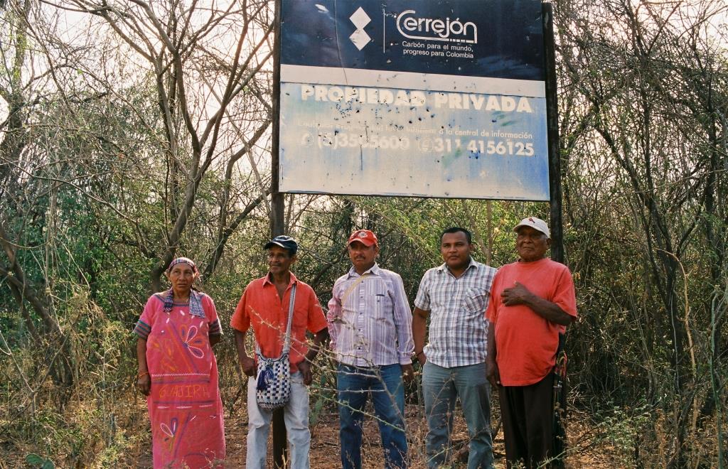 The Wayúu people standing in front of the sign that the exploiting mining company El Cerrejón has put in Tamaquito
